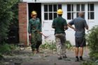 Workers clearing debris as a homeowner looks on at 24th Street and N. Wakefield Street