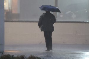 Man holding umbrella as storm brings heavy rain, wind and flooding on 2/24/16