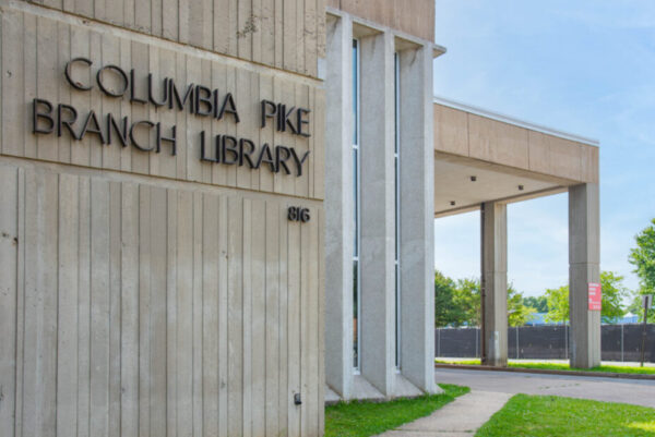 Exterior of Columbia Pike Branch Library with a concrete wall and tall glass windows.