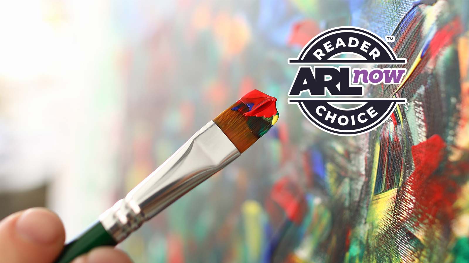 Close-up of a paintbrush with red, yellow and blue paint, painting a vibrant canvas, with a circular 'Reader’s Choice AR Now' badge in the upper right.