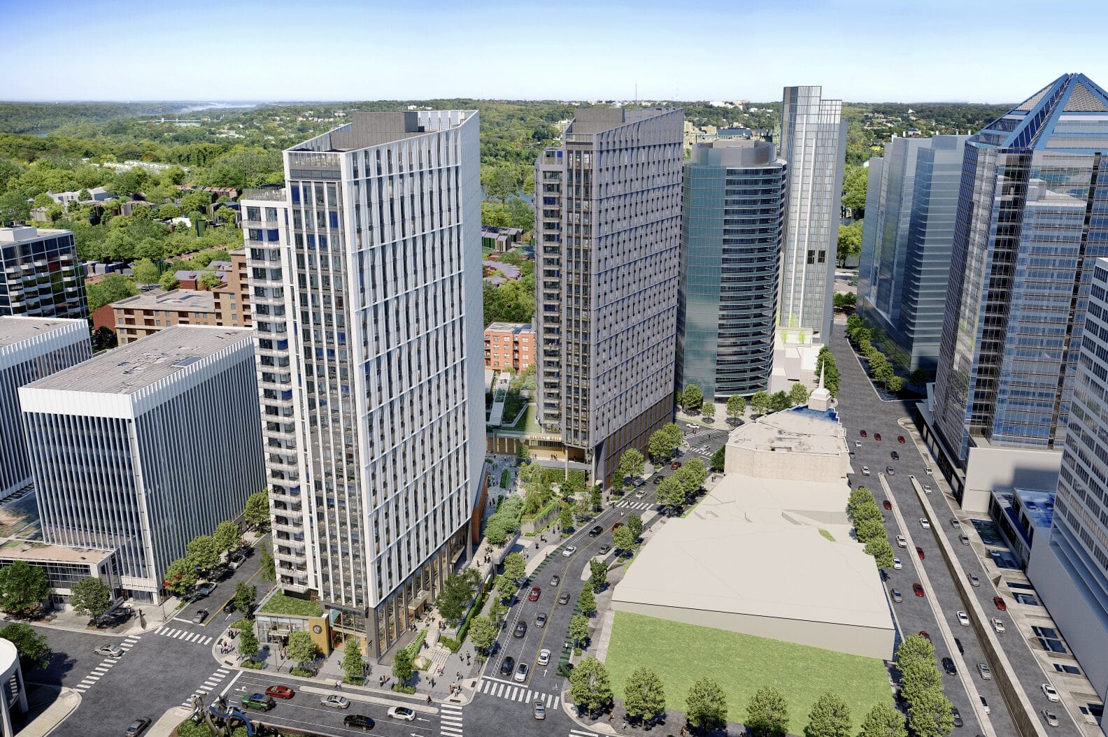 Aerial view of a modern downtown with tall glass skyscrapers, tree-lined streets, and a large open plaza in the foreground.