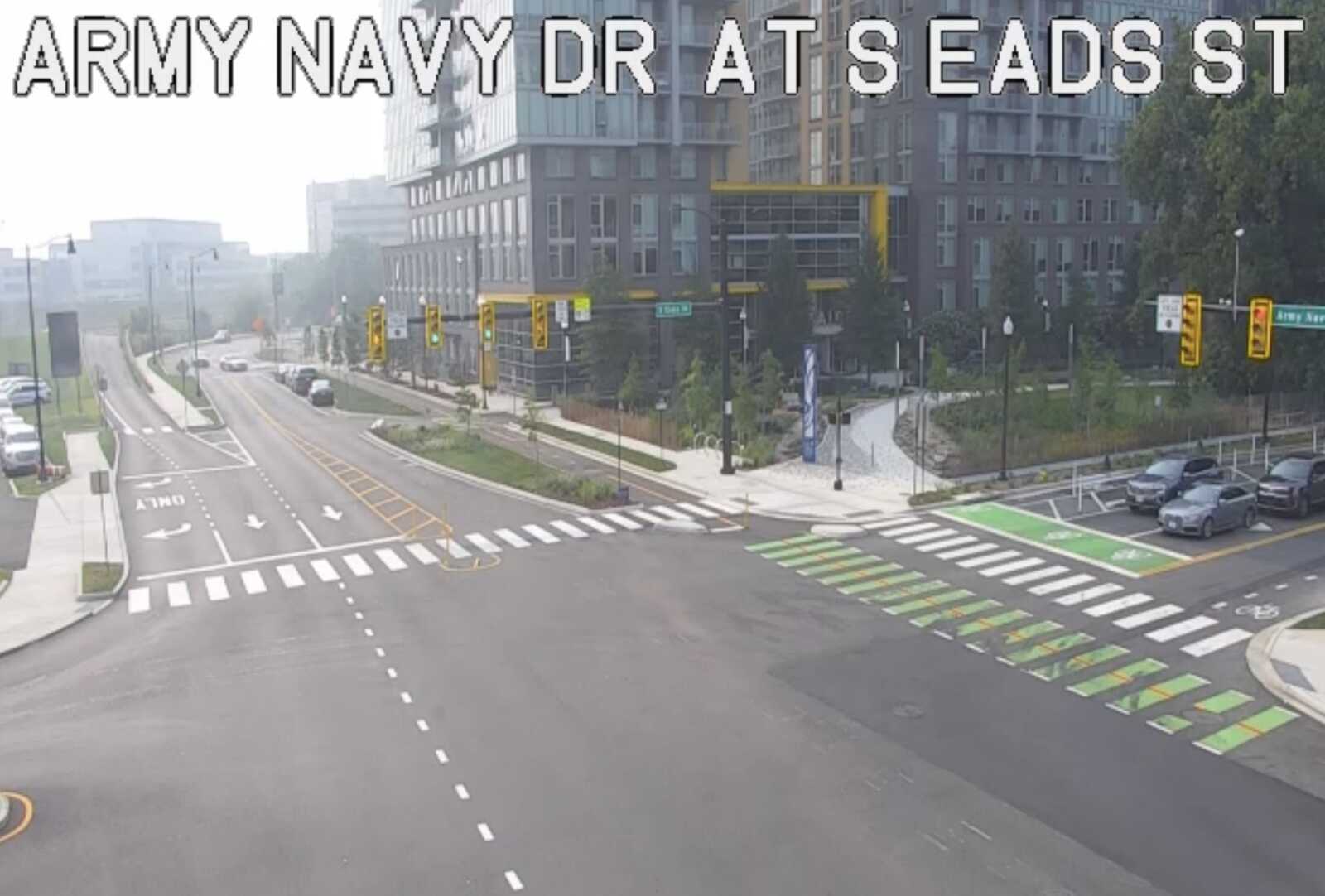 Bird's-eye view of an urban intersection with crosswalks, bike lane markings, traffic signals, and modern buildings.