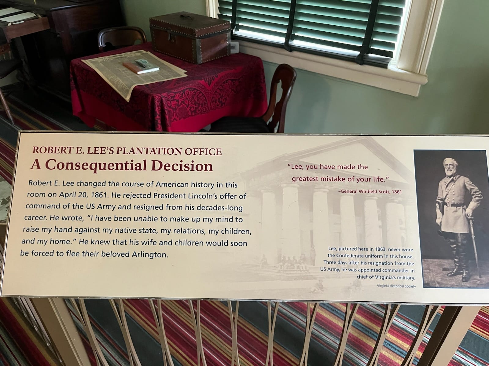 Museum display panel titled "A Consequential Decision" about Robert E. Lee, with a portrait of Lee and a columned building image in the background, plus text.”