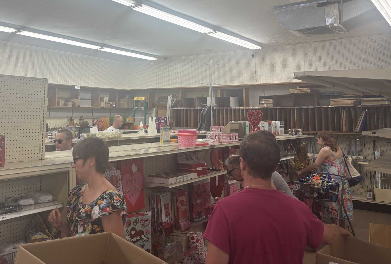 Shoppers browse Valentine-themed items near a checkout counter in a store.