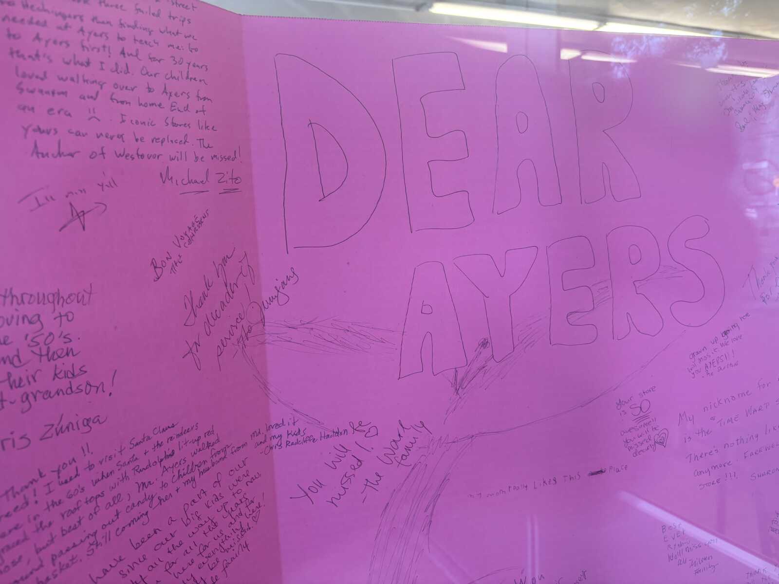 Pink display panel covered in handwritten messages with large outlined text reading 'DEAR AYERS' and surrounding notes.
