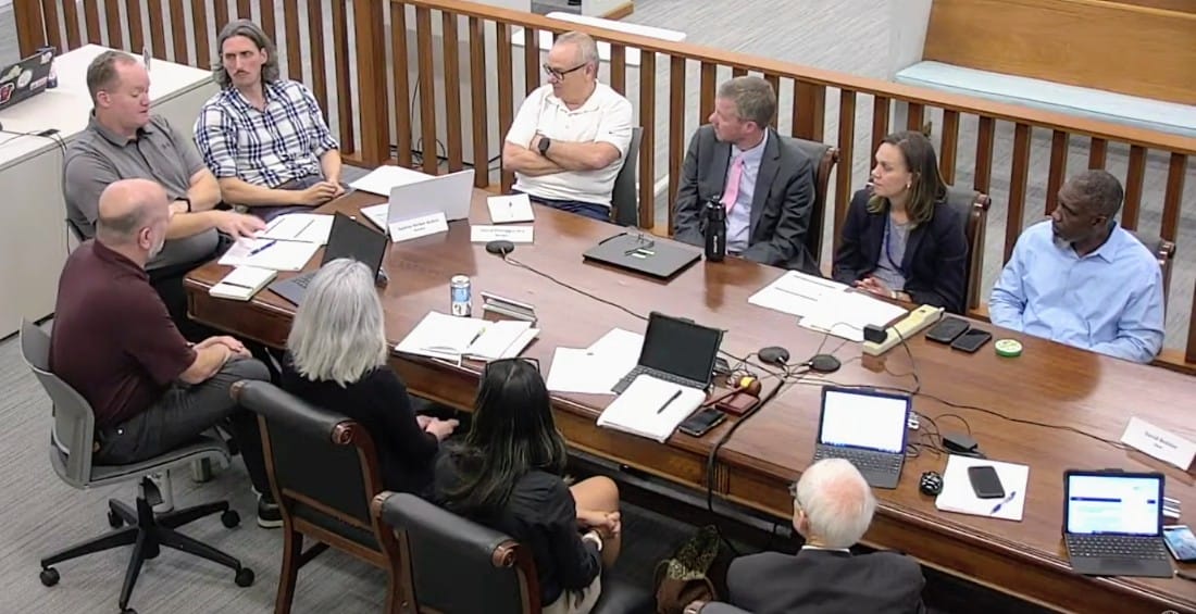 Falls Church City Council work session on snow-removal issues (screenshot via City of Falls Church) | ARLnow Nine professionals sit around a wooden conference table in a boardroom, with laptops, papers, and nameplates in front of them.