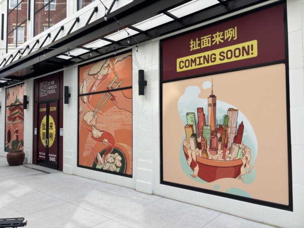 Storefront with colorful murals advertising an upcoming restaurant; a yellow 'COMING SOON!' sign and Xi'an Famous Foods branding visible above the door.