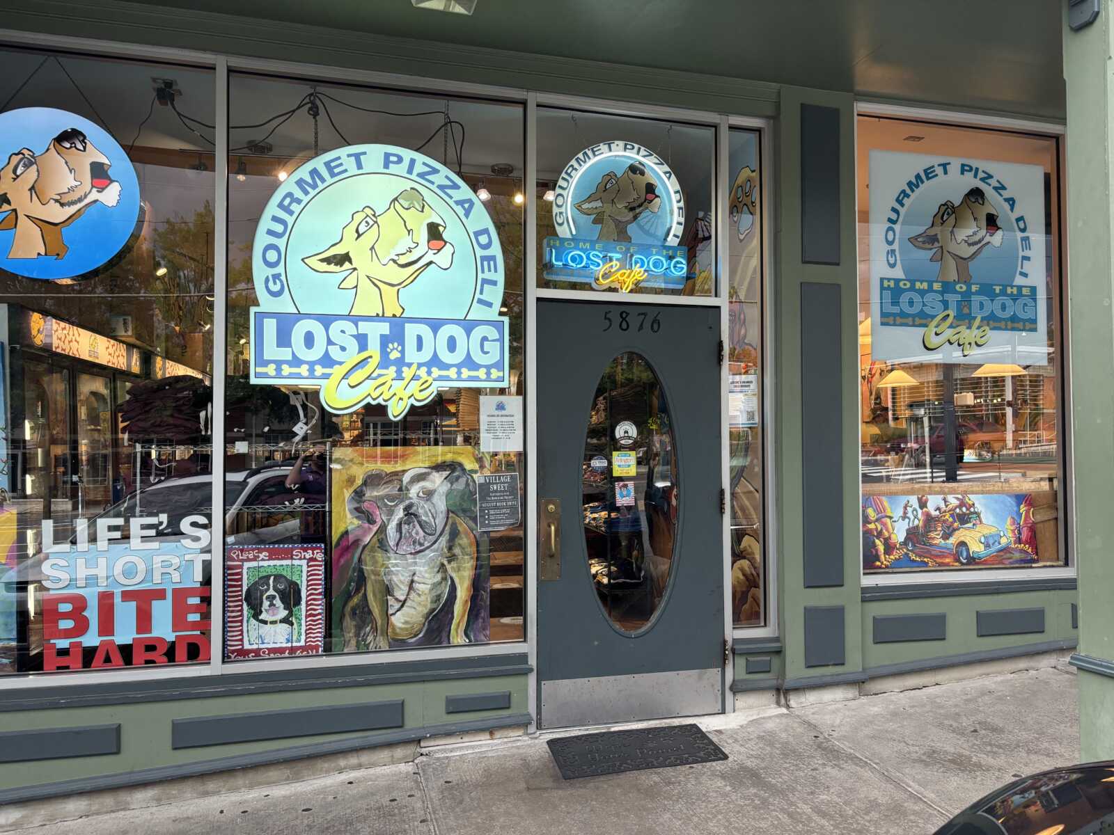 Storefront of Lost Dog Café with large window signs showing a cartoon dog and turquoise branding.