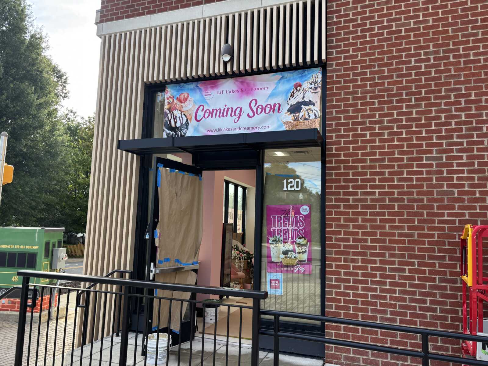 Storefront under renovation with a 'Coming Soon' banner for Lil' Cakes & Creamery above the glass door.