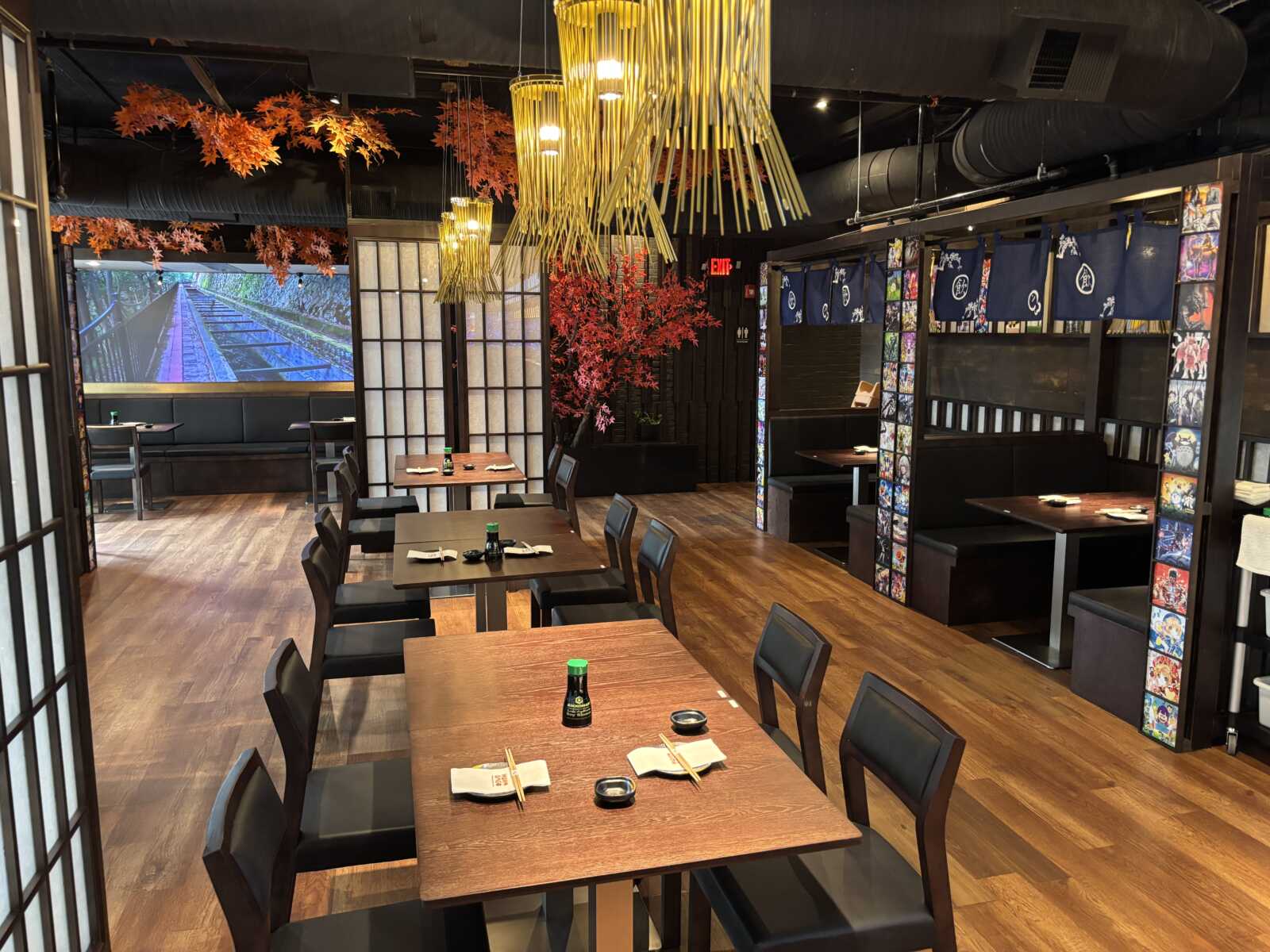 Wooden tables and chairs in a cozy restaurant, with orange autumn leaves and warm hanging lights overhead.