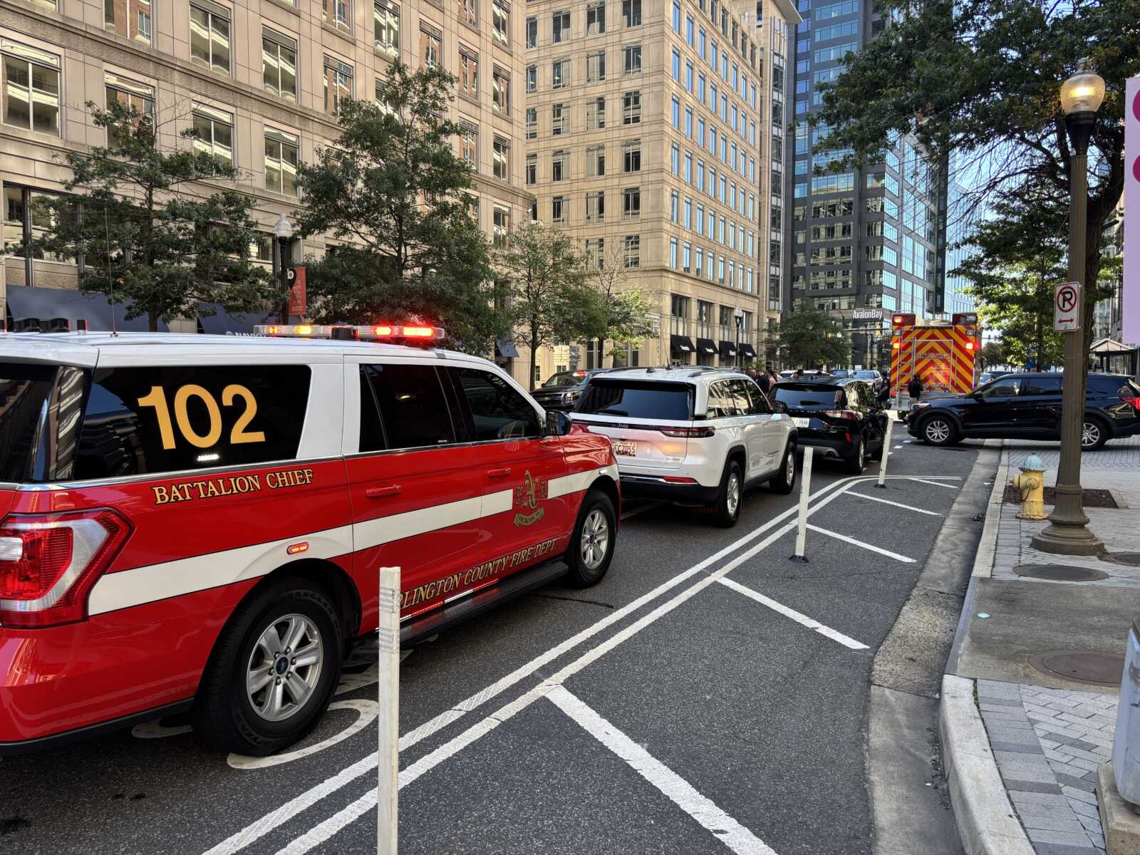 Emergency response scene on a city street with a red Battalion Chief SUV and flashing lights in the foreground.