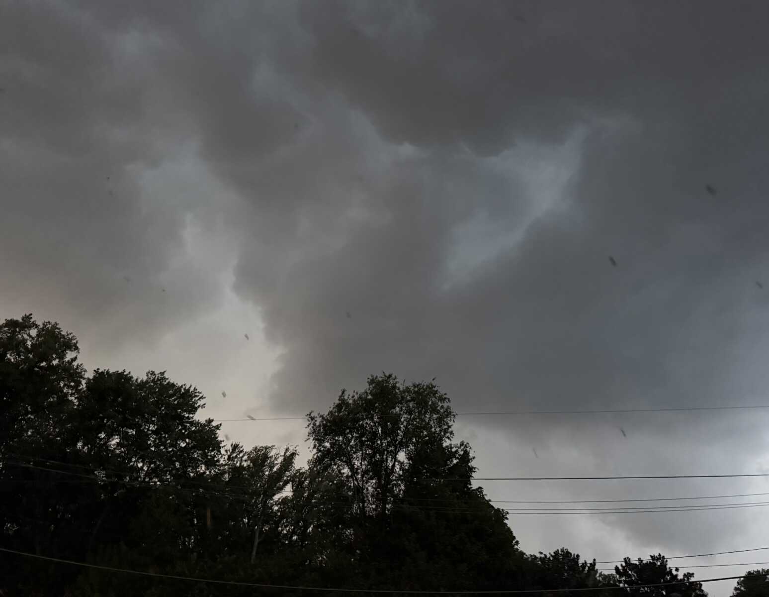 Storm arriving in Arlington last night (staff photo) | ARLnow Dark, heavy storm clouds loom over a tree line with power lines in the foreground.