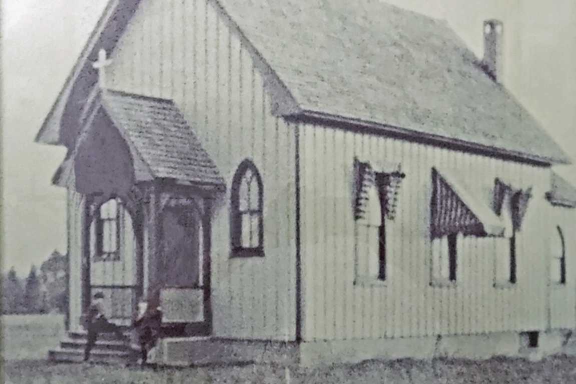Original St. John's Episcopal Church in the early 20th century (courtesy Glencarlyn Civic Association) | ARLnow Small wooden church with a steep roof, front porch, arched window, and cross on the roof peak in a rural setting.