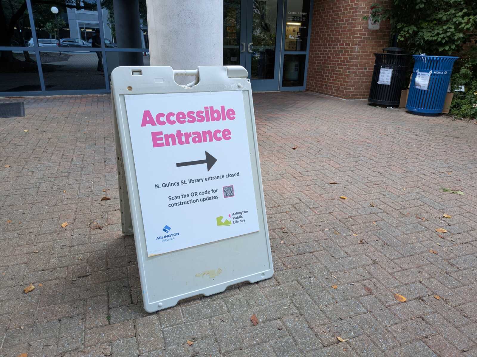 Outdoor sign directing to Accessible Entrance with a right-pointing arrow in front of a library building.
