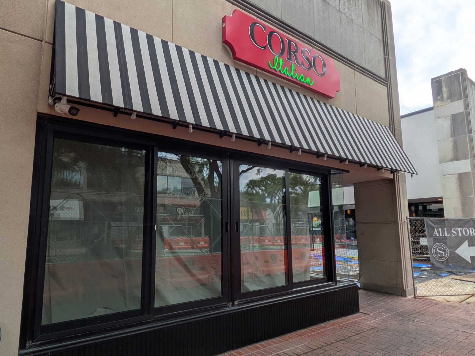 Front of a Corso Italian restaurant with a black-and-white striped awning and large glass windows beneath a red sign.