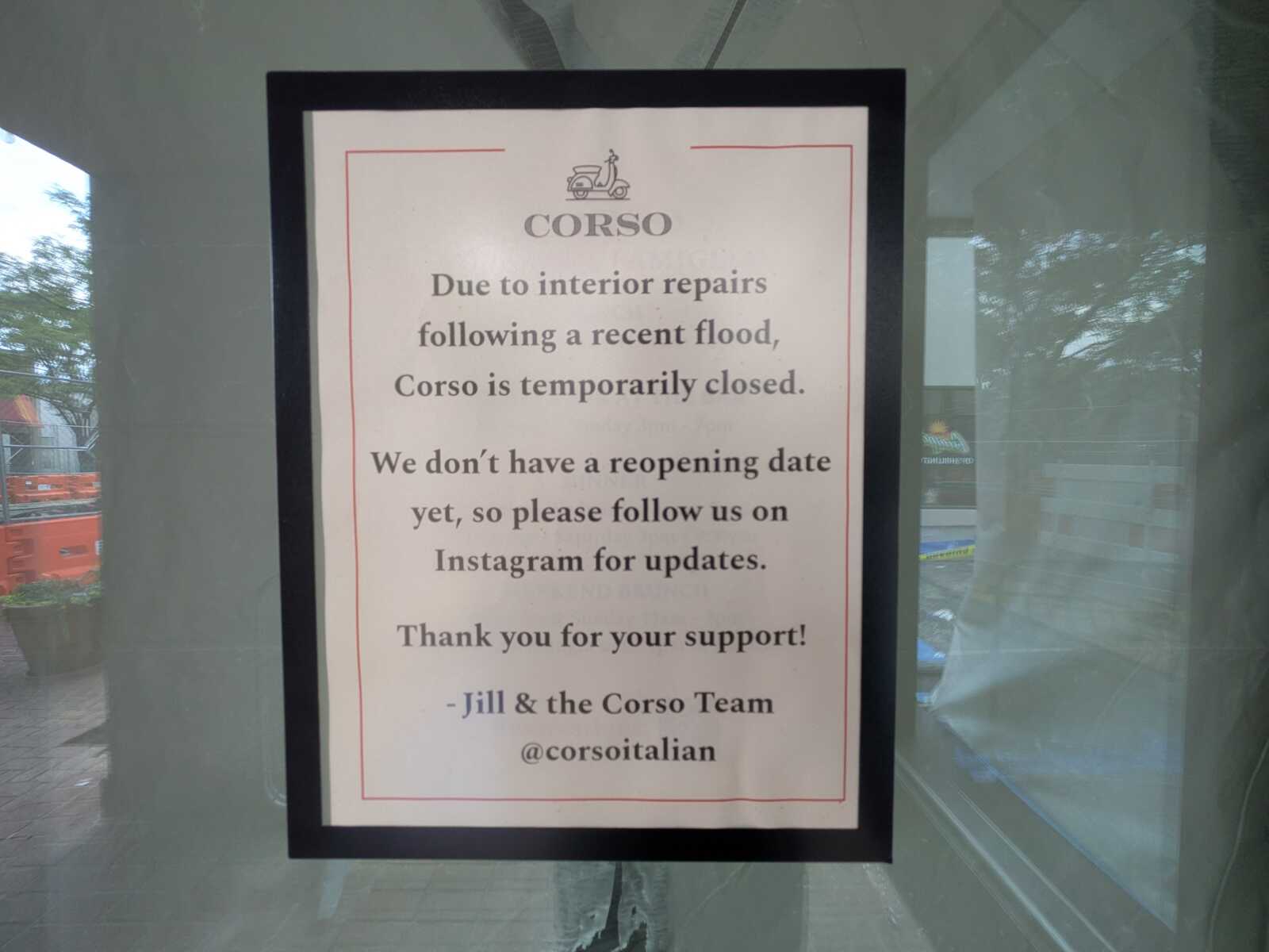 Framed sign on a glass door: Corso is temporarily closed due to interior repairs after a flood; follow Instagram for updates.