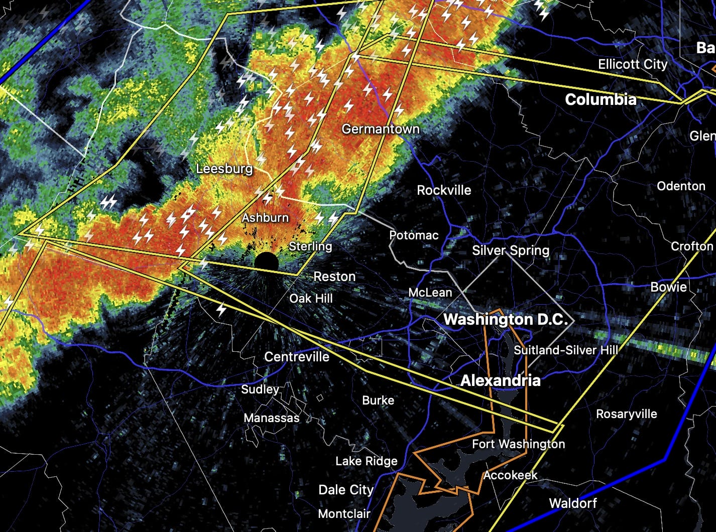 Radar map showing a line of intense storms west of the DC metro area (Germantown, Ashburn, Leesburg) with red/orange colors and lightning icons over the region with city labels nearby for context