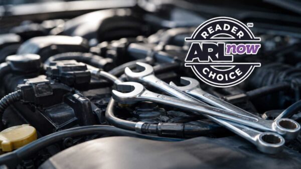 Close-up of a car engine with two wrenches resting on top; a circular badge overlays the right side saying 'Reader's Choice'.