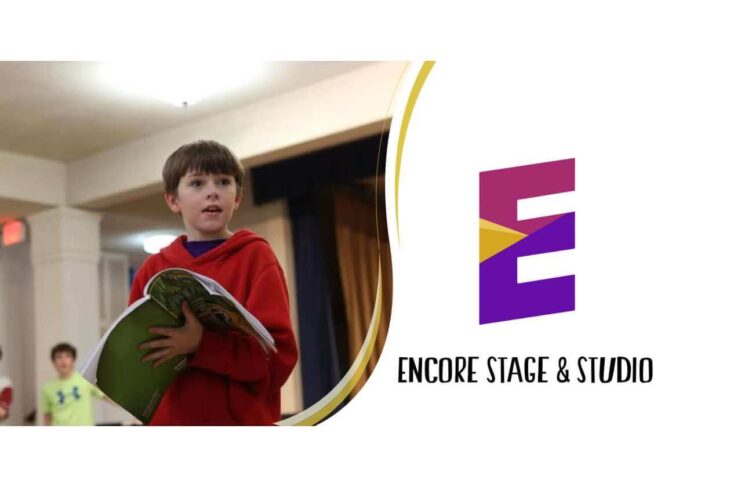 Young boy in a red hoodie reads a green book on a stage, logo and 'Encore Stage & Studio' visible to the right