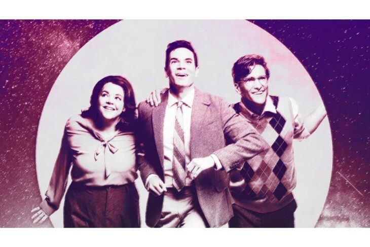 Three friends wearing vintage clothing walk arm-in-arm, smiling, against a pink-purple retro backdrop with a large white circle.