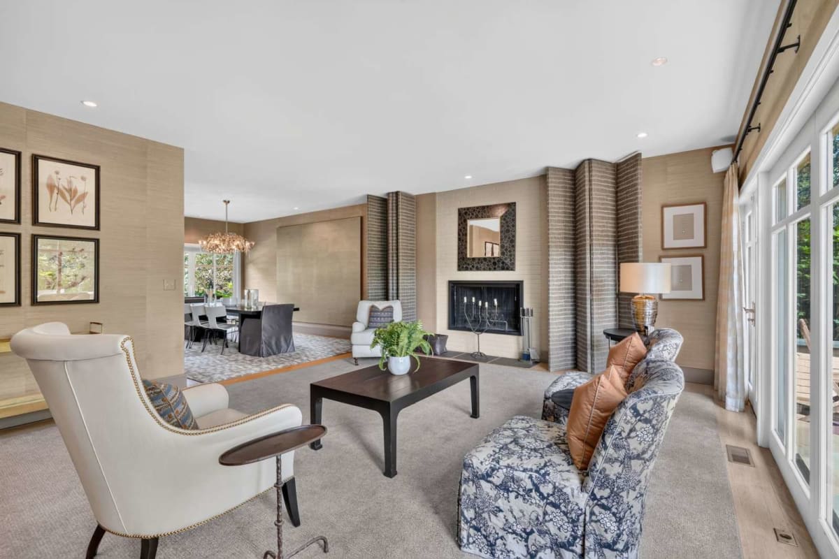 Bright living room with a gas fireplace, two patterned armchairs, a white recliner, and a glass door to the patio.