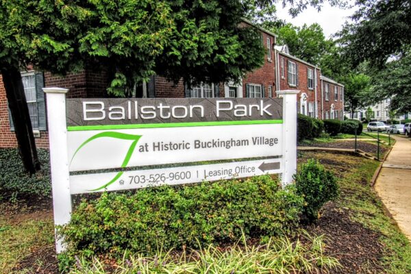 Sign for Ballston Park at Historic Buckingham Village with leasing office phone number 703-526-9600 on a suburban street.