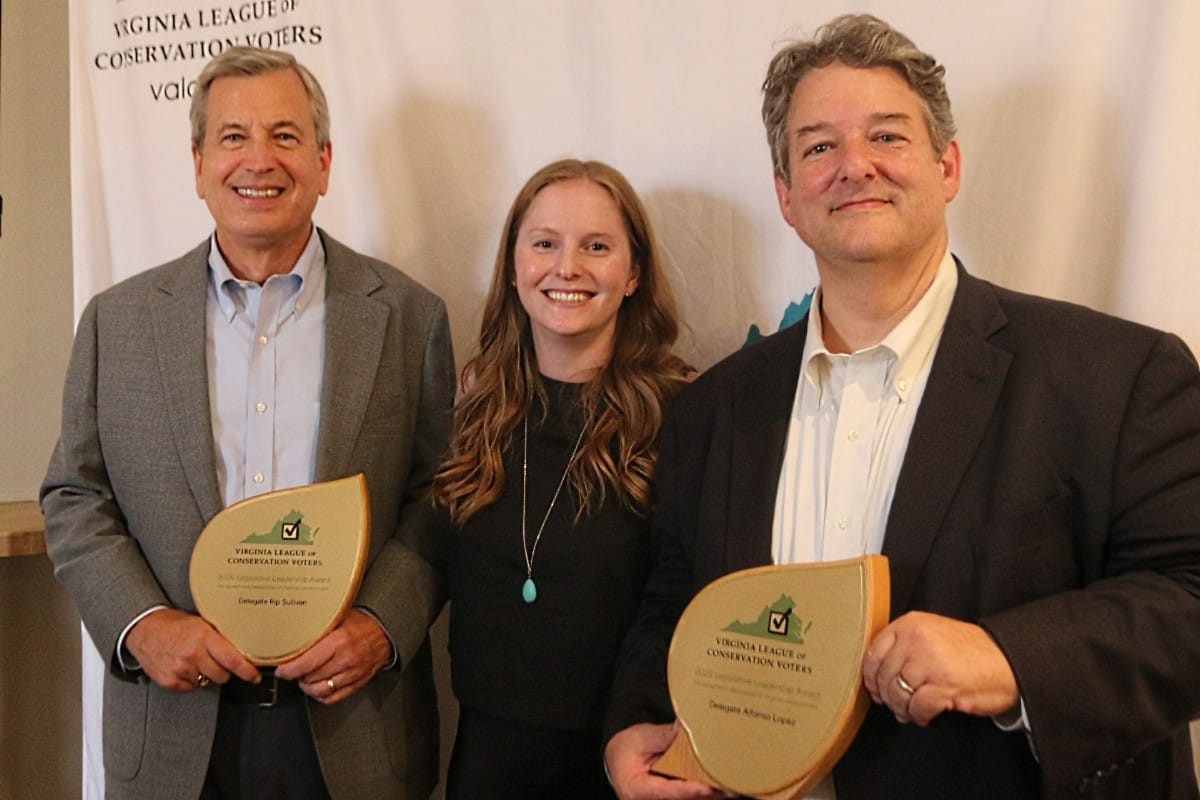 Three people pose with awards at a Virginia League of Conservation Voters event, standing in front of a banner.