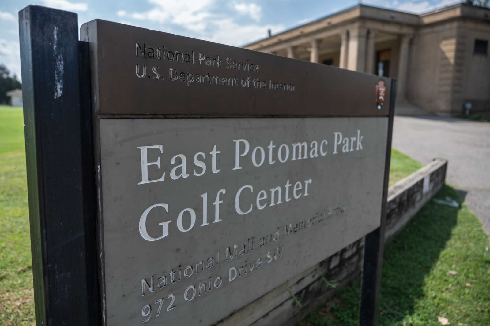 Sign reading East Potomac Park Golf Center with National Park Service branding above the text, outdoors near a building.