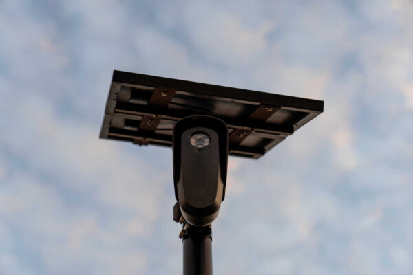 Solar-powered street light mounted on a pole, viewed from below against a blue sky