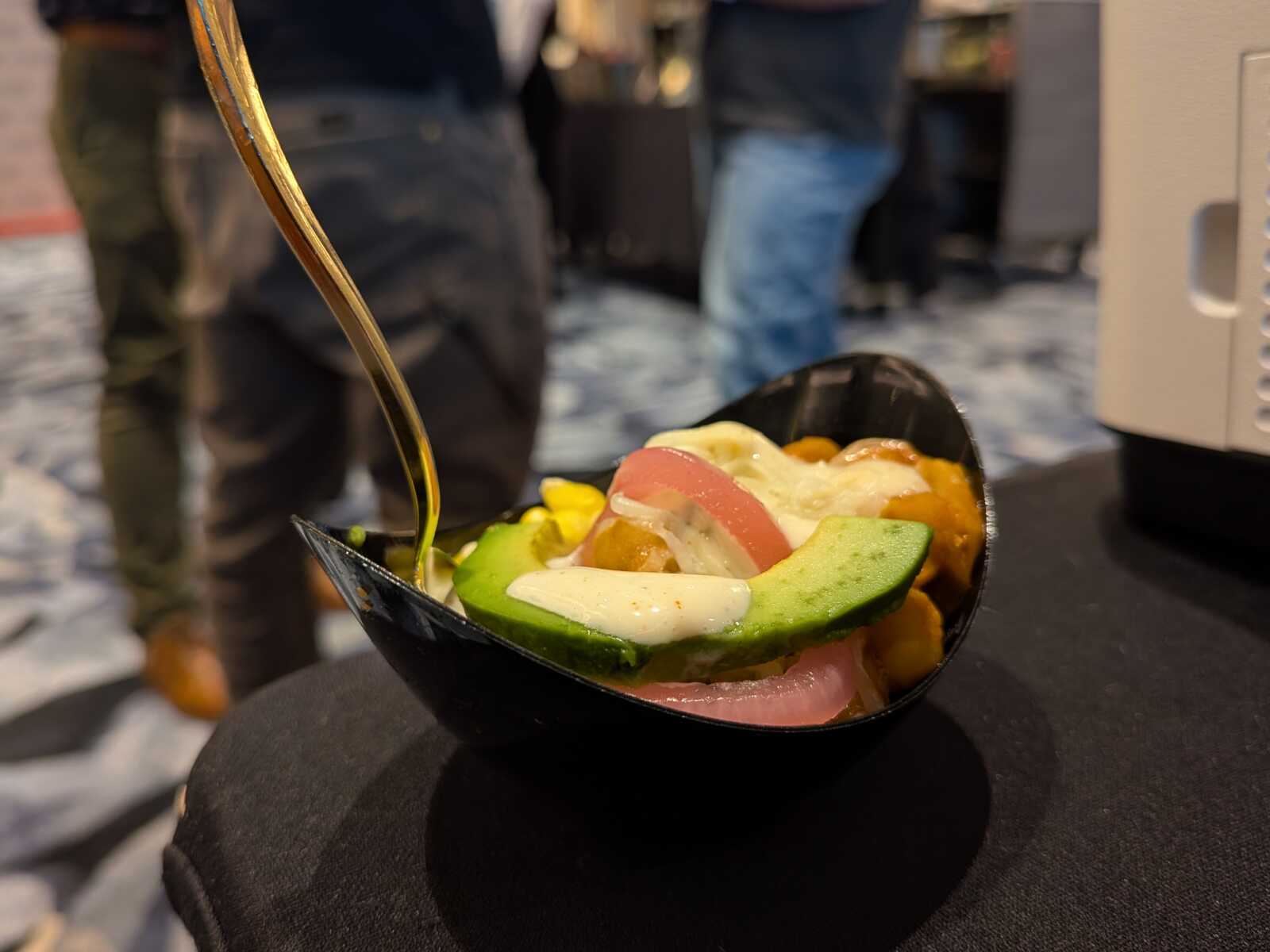 Bowls of poke with avocado slices, tuna, and sauces in a black bowl on a dark table.