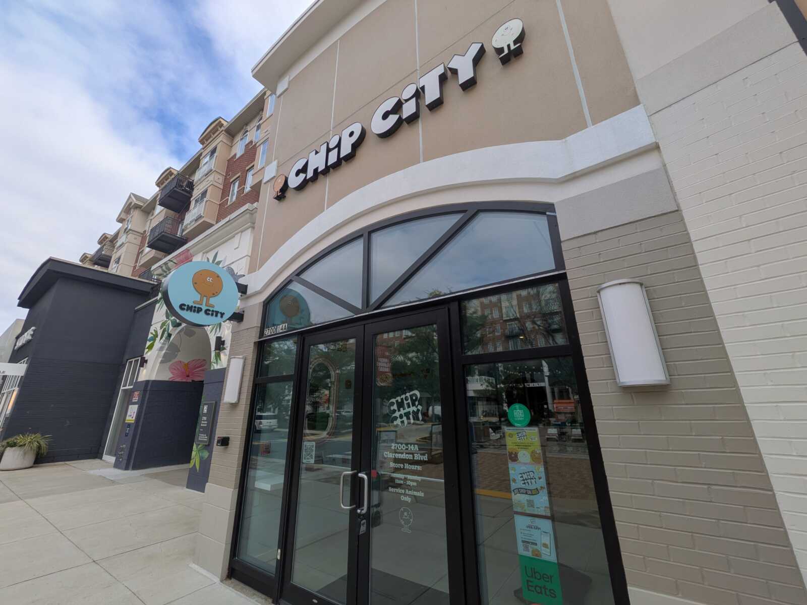 storefront of Chip City featuring large black-and-white sign above glass doors; round blue sign with a cartoon cookie logo hangs to the left