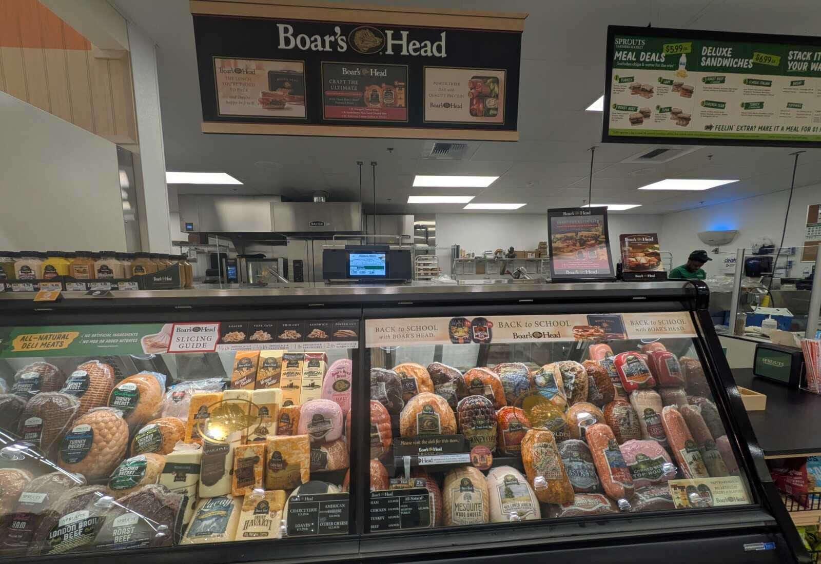 Deli counter at Boar's Head with a glass display case full of assorted deli meats and cheeses.
