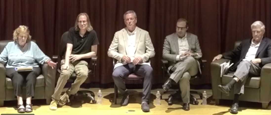 Panel of former Arlington Historical Society presidents (screenshot via AHS) | ARLnow Panel of five adults seated in chairs on a stage, appearing to participate in a discussion. The woman on the far left has a notebook; others sit attentively.