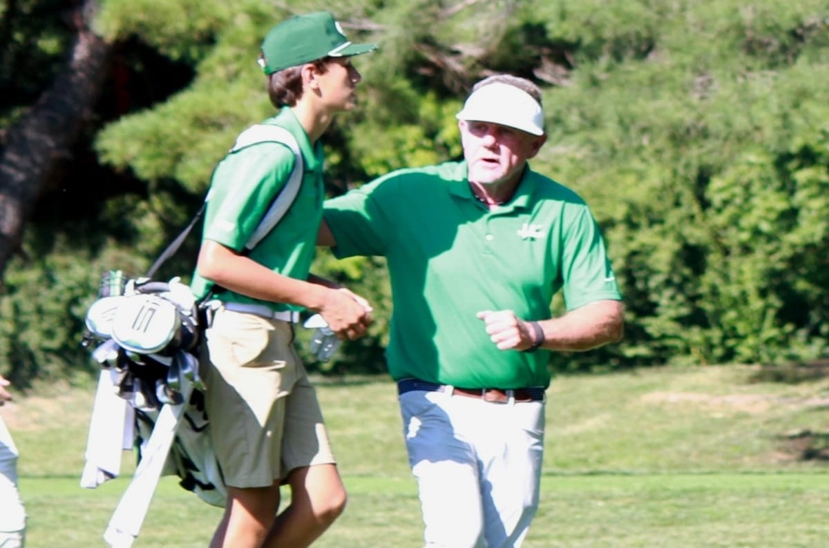 Wakefield coach Dave Knorr, right, talks with player Flynn Uscinski (photo by Dave Facinoli) | ARLnow Two golfers on a sunny course shake hands; a young player with a golf bag walks beside an older coach in a visor.