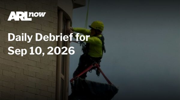 Worker in a helmet and safety harness rappelling down the exterior of a brick building, with 'Daily Debrief for Sep 10, 2016' overlay from ARL Now