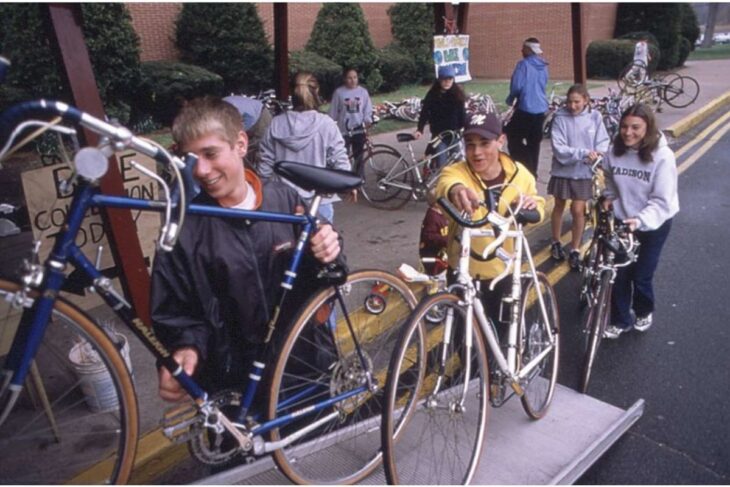 Group of students with bikes on a loading ramp outside a school, preparing for a bike event or ride.