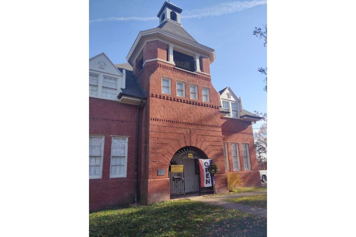Red brick building with a small tower and arched entrance; a vertical OPEN banner hangs at the door.