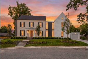 Two-story modern house with a glass connector, front steps, and a manicured lawn at sunset.