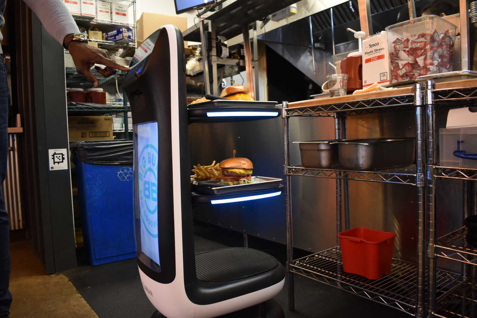 Autonomous food robot delivering a burger and fries on a tray in a kitchen.