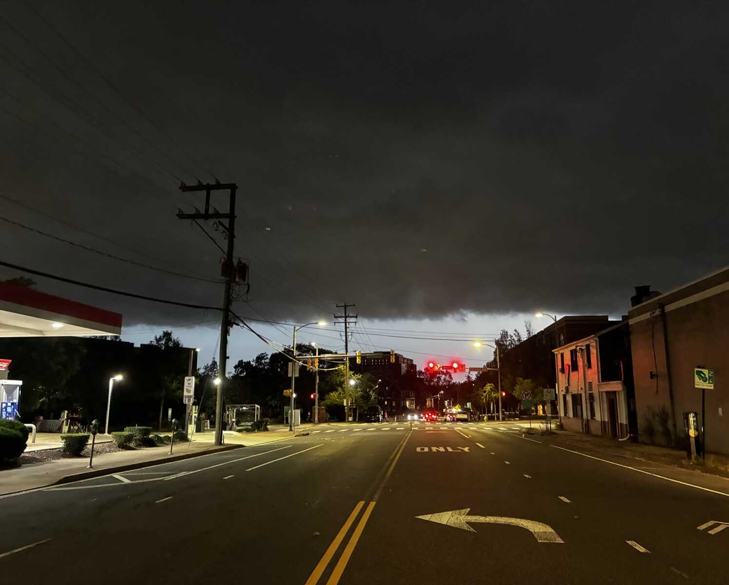 Cold front and storm clouds arrive in Arlington over the weekend (courtesy George Brazier) | ARLnow Dark, heavy storm clouds press over a city street at night, with red traffic lights glowing ahead.