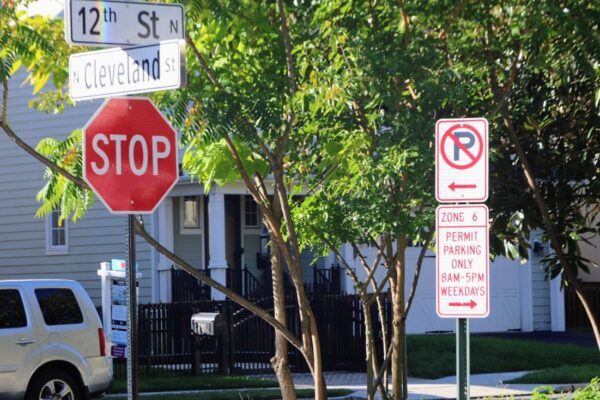 Stop sign at the intersection of 12th St N and Cleveland St with a nearby no-parking/permit parking sign nearby.
