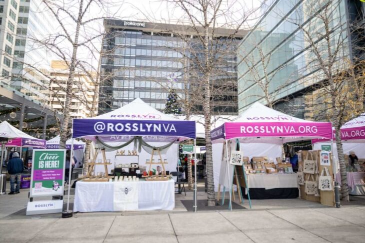 Outdoor market in Rosslyn with white and purple tents, crafts stalls, and a Christmas tree in a modern plaza.