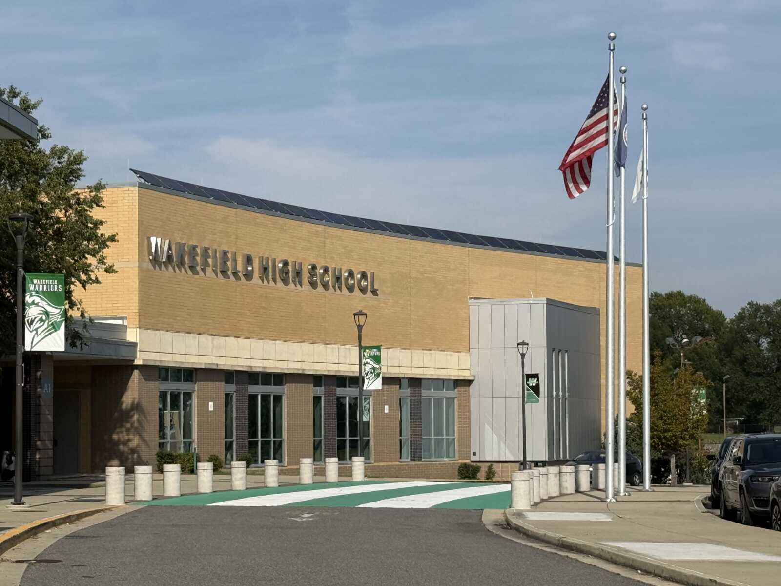 Wakefield High School exterior with flagpoles and American flag in front of brick building